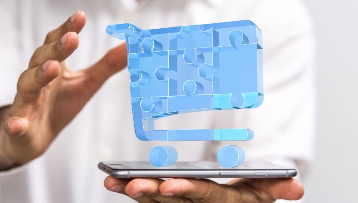 Hände halten ein Smartphone, darüber schwebt ein digitaler Einkaufswagen – Symbol für die Analyse und Optimierung von Versicherungskosten.